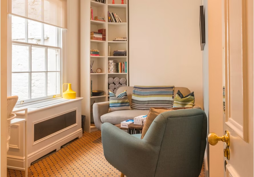 Sunee's consulting room, a warm, softly lit space with armchairs and bookshelves